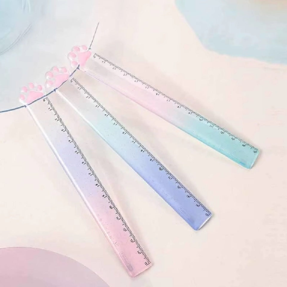 une règle pailletée en forme de patte de chat toute mignonne avec ses coussinets roses. graduée jusqu'à 15 cm, elle est trop kawaii avec son dégradé de couleur pastel