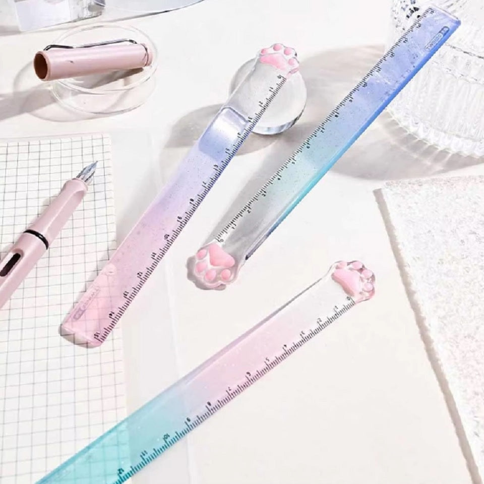 une règle pailletée en forme de patte de chat toute mignonne avec ses coussinets roses. graduée jusqu'à 15 cm, elle est trop kawaii avec son dégradé de couleur pastel