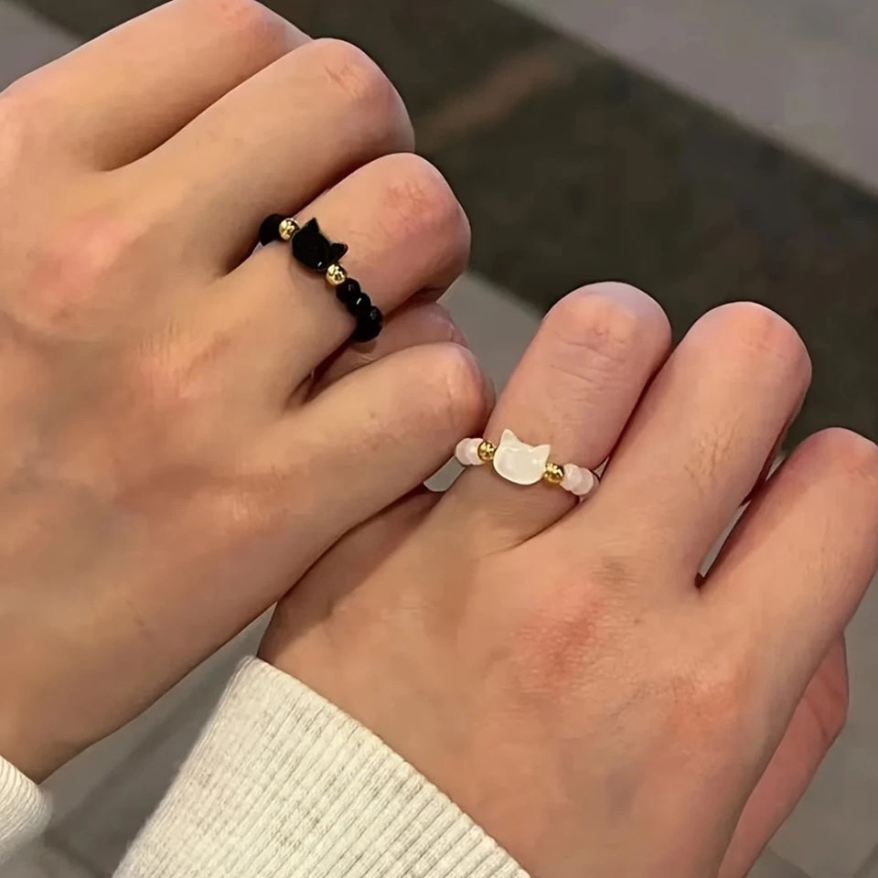 une bague taille élastique toute en parles et une breloque perles en forme de tête de chat. Disponible en coloris noir ou blanc.