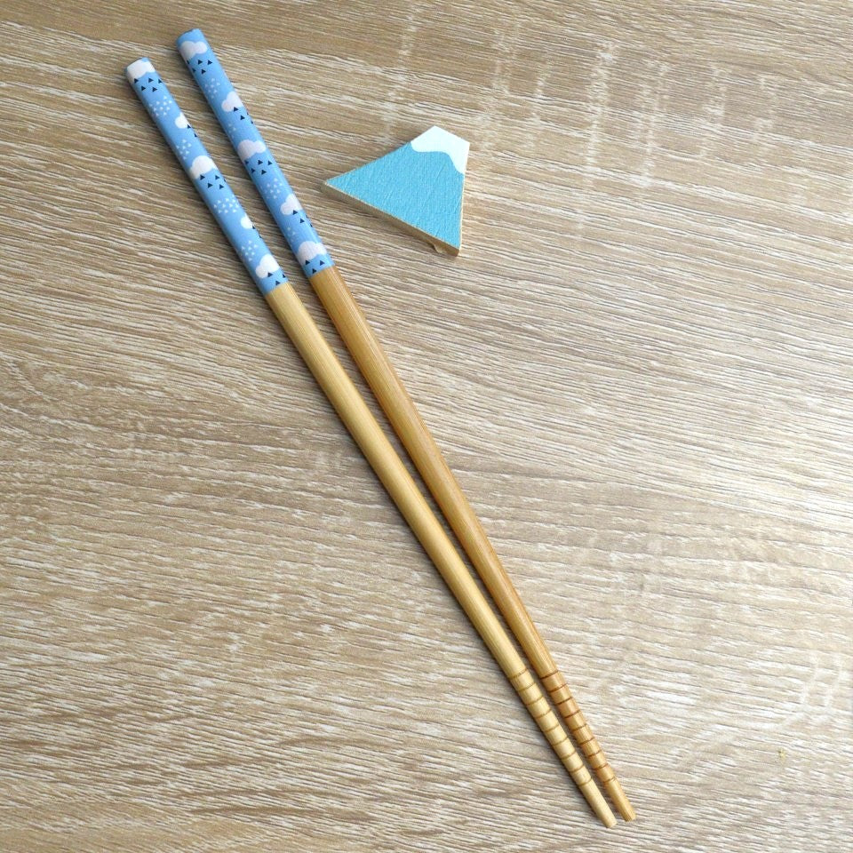 une paire de baguette japonaise décoré d'un motif de ciel et son repose baguette en forme d mont Fuji. Rappel du Japon qui habille avec raffinement votre table.