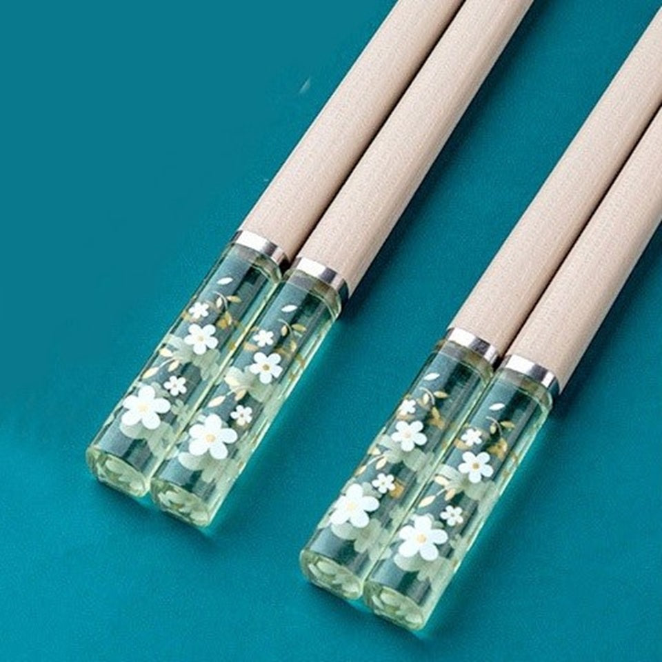 Une paire de baguettes japonaises élégantes au motif de fleurs de sakura. Le bout des baguettes est transparent et renferme des fleurs de sakura