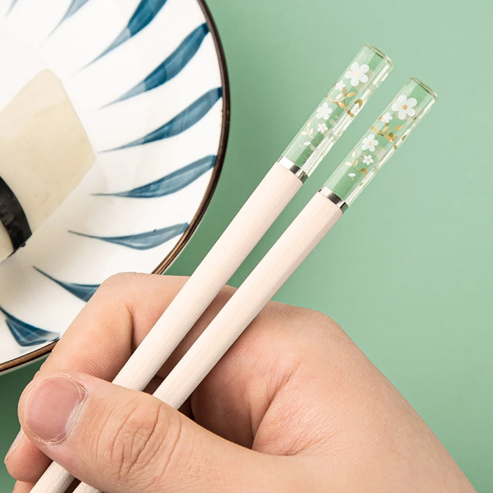 Une paire de baguettes japonaises élégantes au motif de fleurs de sakura. Le bout des baguettes est transparent et renferme des fleurs de sakura