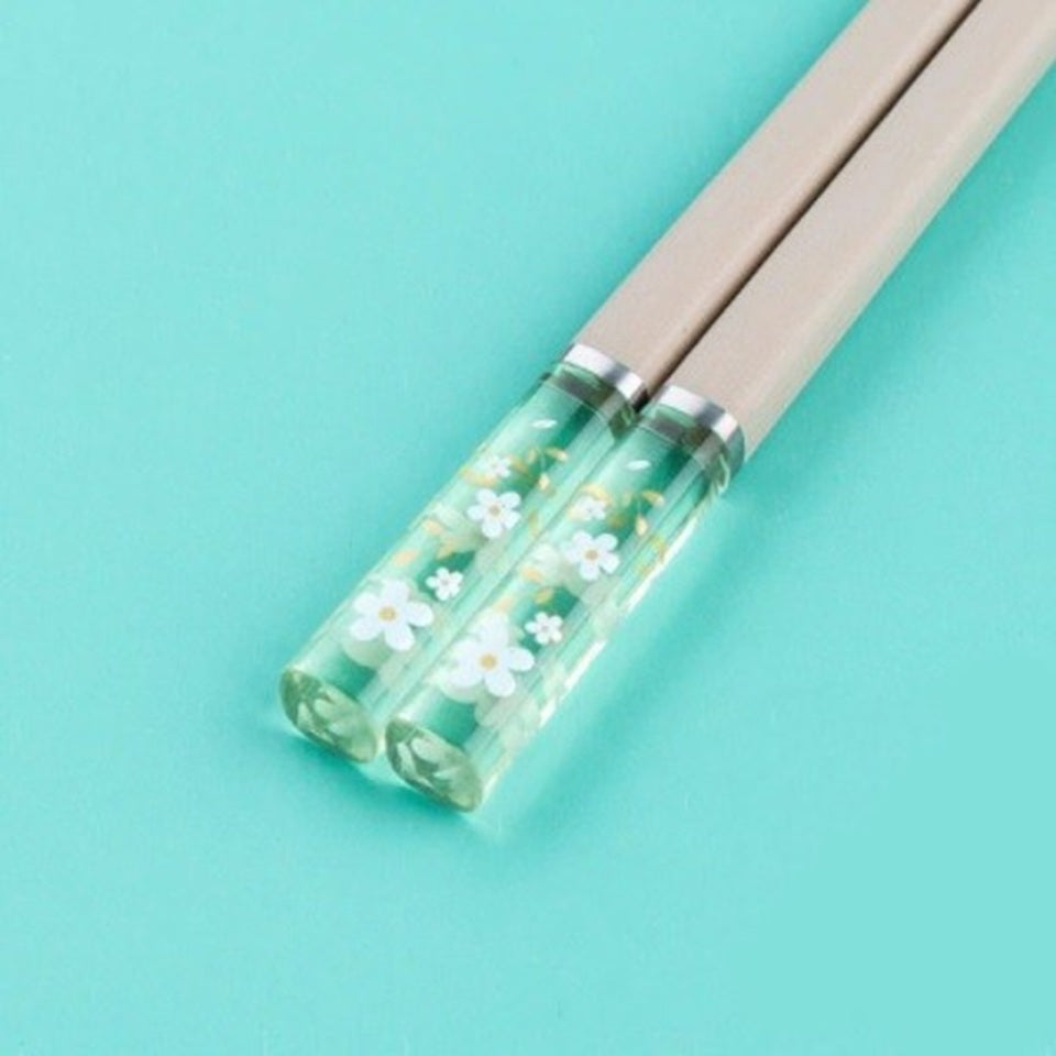 Une paire de baguettes japonaises élégantes au motif de fleurs de sakura. Le bout des baguettes est transparent et renferme des fleurs de sakura