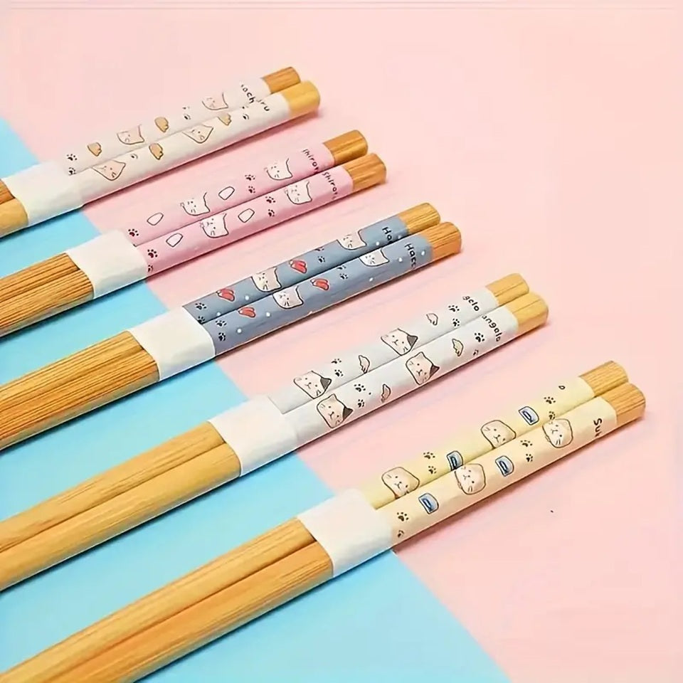 des baguettes japonaises au motif de petits chats et de nourriture. Le design est amusant et très mignon. En bambou, elles sont durables et réutilisables.