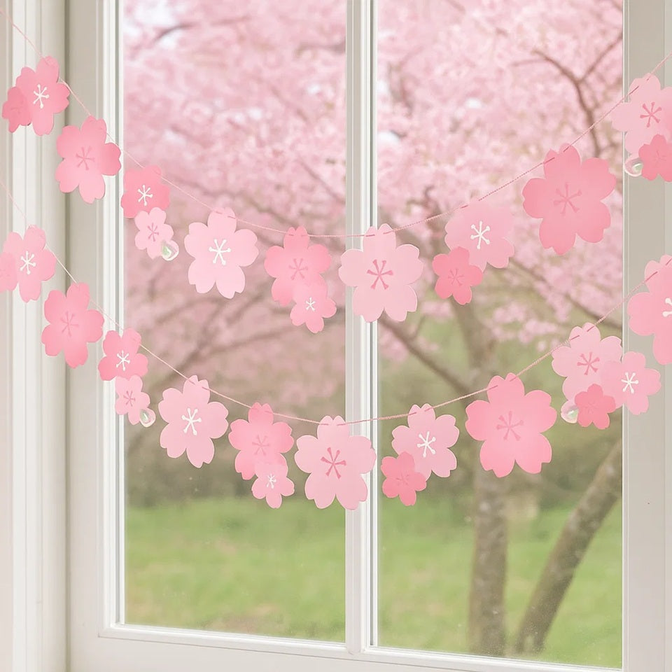 une banderole en papier formée de fleurs de sakura rose. A suspendre avec sa cordelette fournie. Elle ajoute une touche florale et mignonne à une pièce ou un extérieur.