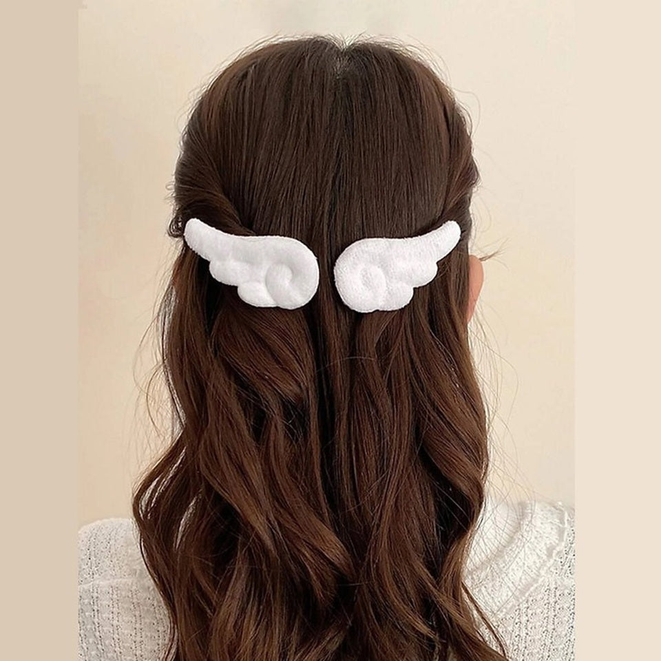 une paire de barrettes à cheveux en forme d'ailes d'ange blanches ou roses. Pour un look kawaii et romantique elles sont parfaites. En matière peluchée, elles sont toutes douces.