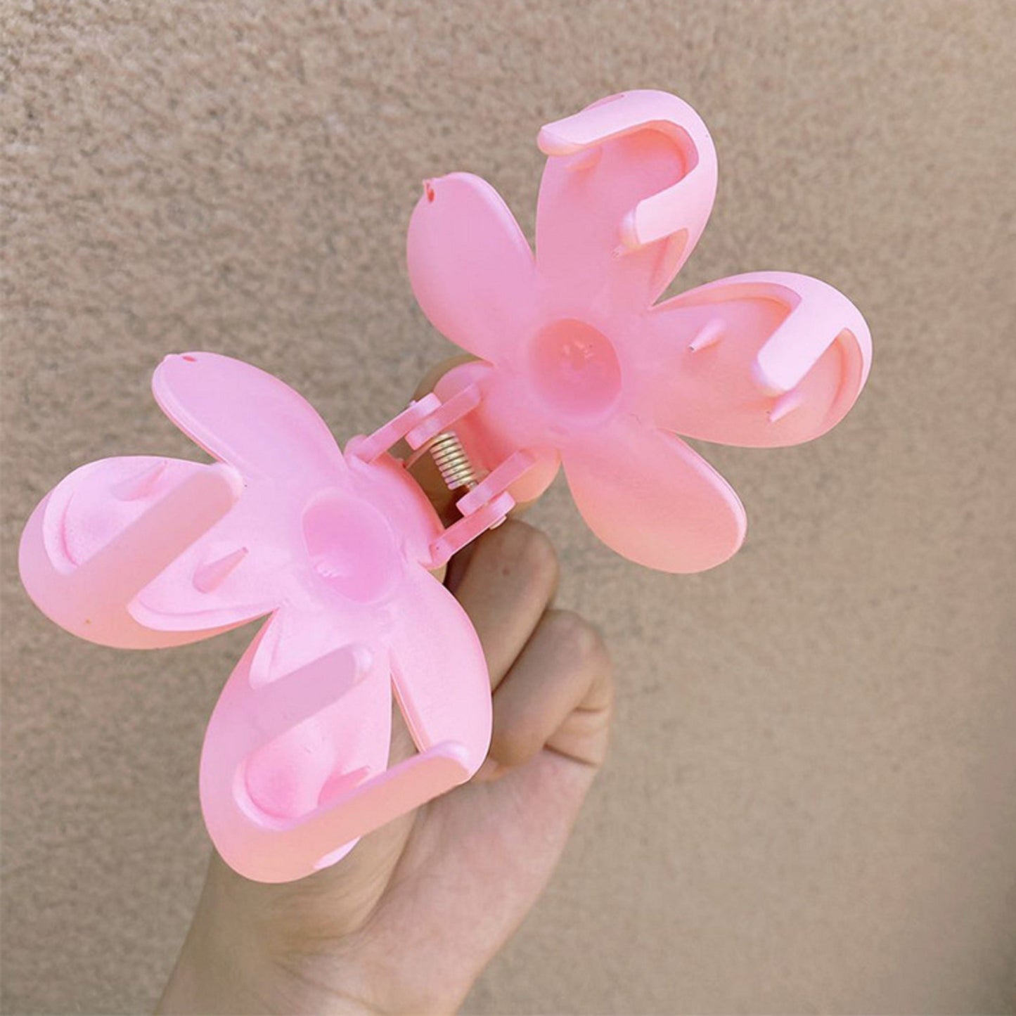 une pince à cheveux rose en forme de fleur ouverte. On voit les dents de la pince.