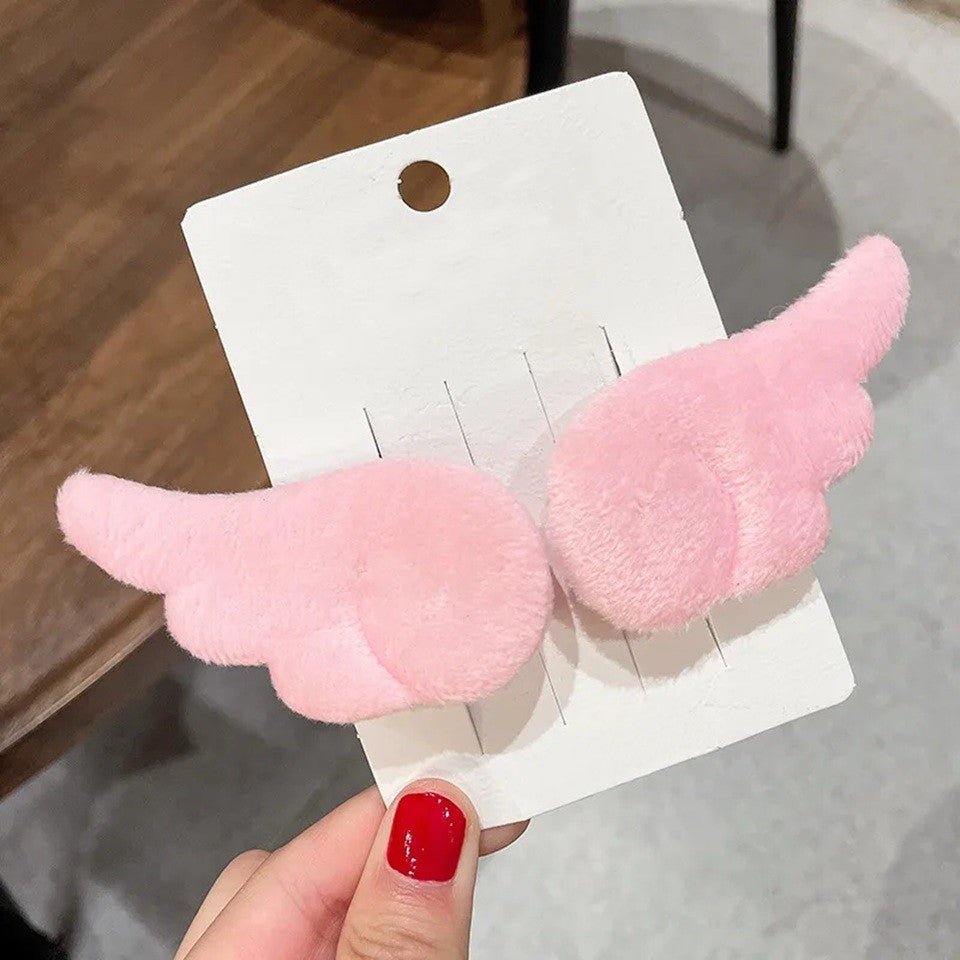 une paire de barrettes à cheveux en forme d'ailes d'ange blanches ou roses. Pour un look kawaii et romantique elles sont parfaites. En matière peluchée, elles sont toutes douces.