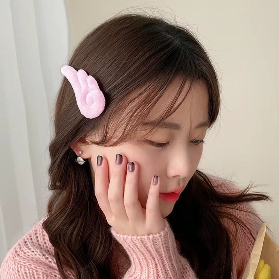 une paire de barrettes à cheveux en forme d'ailes d'ange blanches ou roses. Pour un look kawaii et romantique elles sont parfaites. En matière peluchée, elles sont toutes douces.