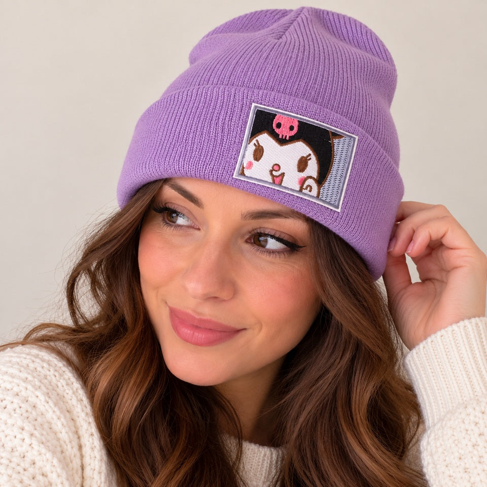Femme portant un bonnet violet lavande en maille côtelée avec broderie Kuromi, personnage kawaii Sanrio. Associé à un pull blanc, ce bonnet doux et chaud au style japonais est présenté sur un fond beige épuré, idéal pour l'automne et l'hiver.