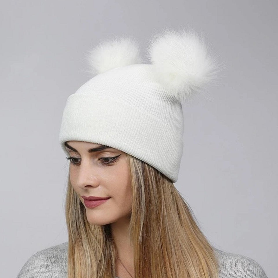 un bonnet blanc doté de deux adorables pompons blancs de chaque côté comme si c'était des oreilles