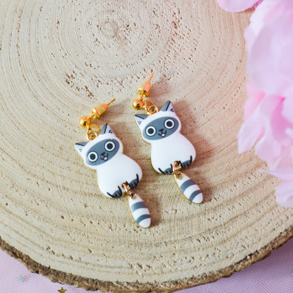 des boucles d'oreilles en forme de chat de toutes les couleurs. Ils ont la queue qui pend indépendamment de leur corps. Ils sont vraiment mignons et stylés