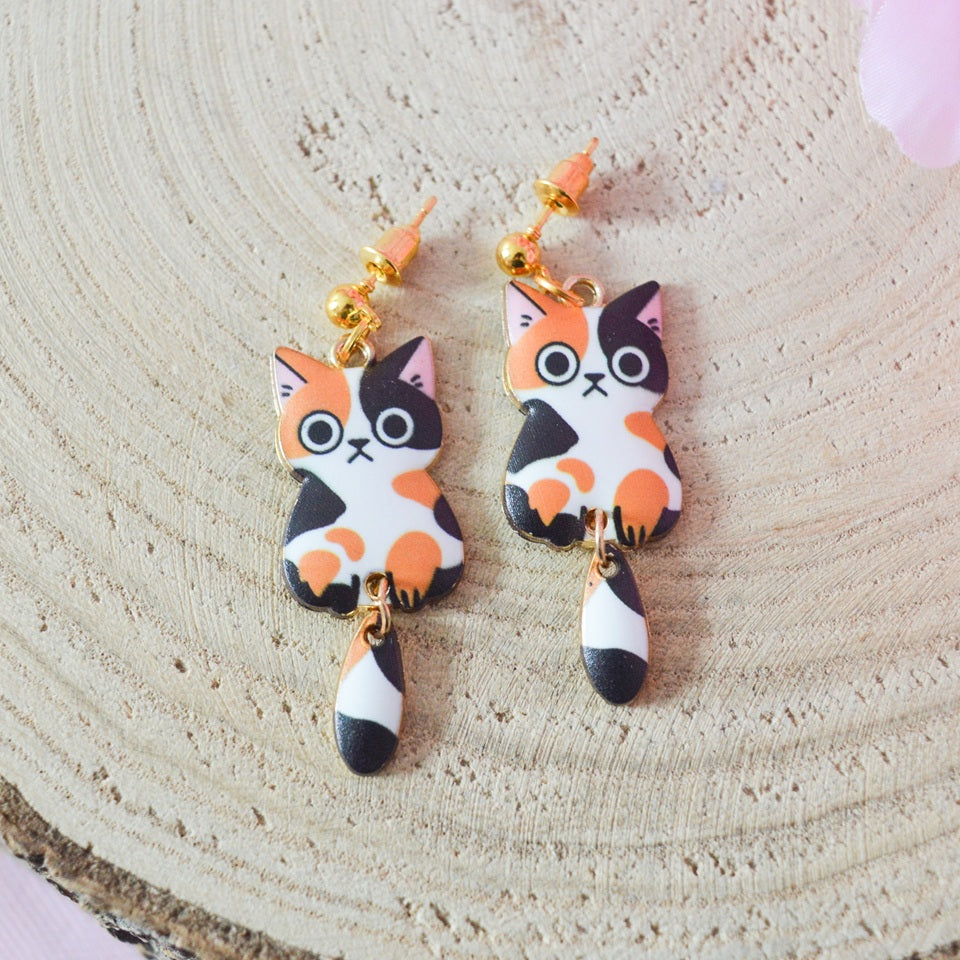 des boucles d'oreilles en forme de chat de toutes les couleurs. Ils ont la queue qui pend indépendamment de leur corps. Ils sont vraiment mignons et stylés