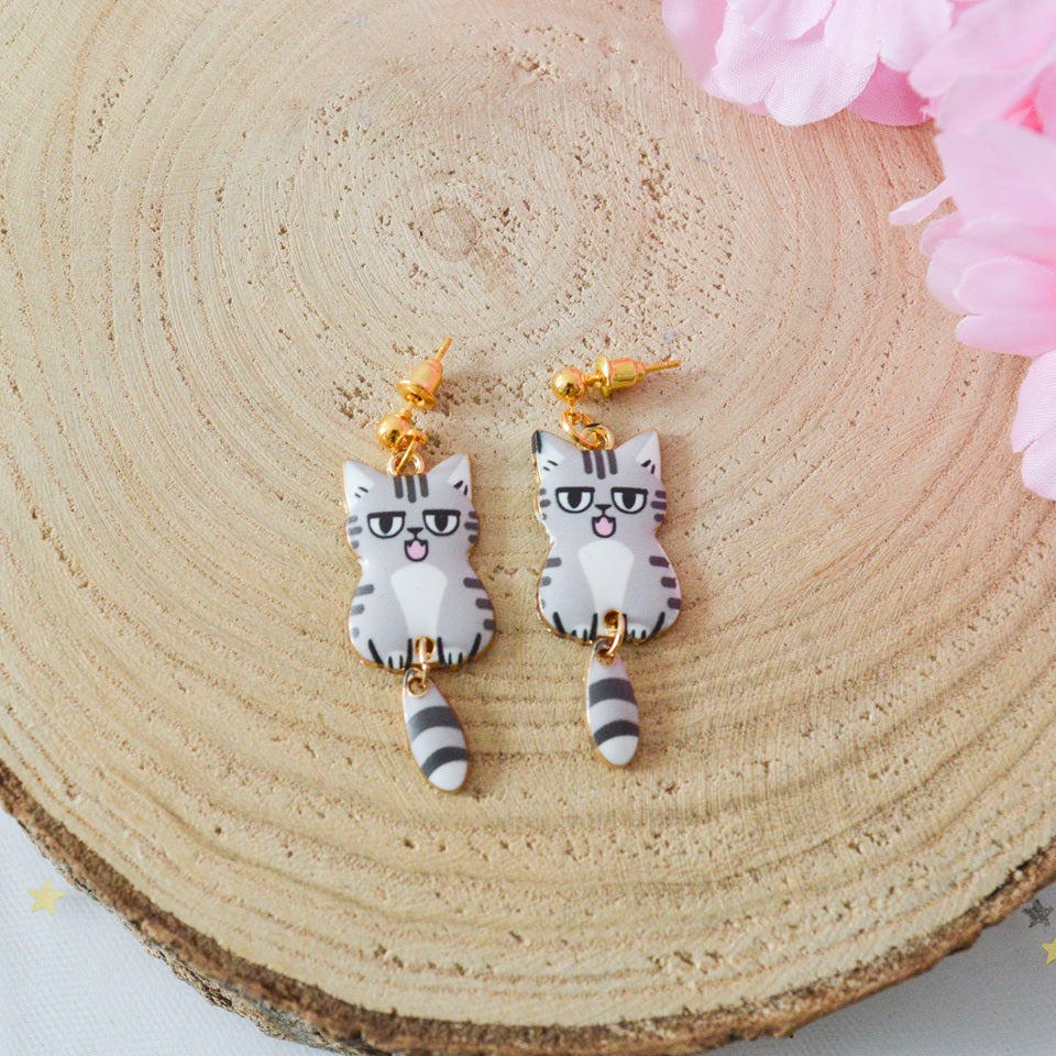 des boucles d'oreilles en forme de chat de toutes les couleurs. Ils ont la queue qui pend indépendamment de leur corps. Ils sont vraiment mignons et stylés