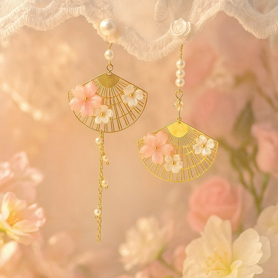 une paire de boucles d'oreilles asymétriques composées d'éventails dorés décorés avec de jolies fleurs de sakura, des perles blanches viennent apporter de l'élégance à l'ensemble.