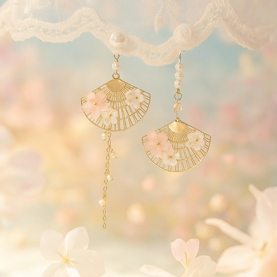 une paire de boucles d'oreilles asymétriques composées d'éventails dorés décorés avec de jolies fleurs de sakura, des perles blanches viennent apporter de l'élégance à l'ensemble.