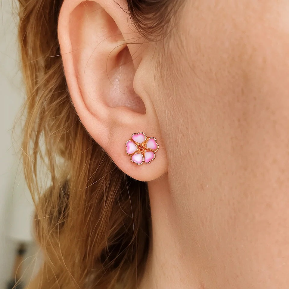 une paire de boucles d'oreilles rose gold en forme de petites fleurs de sakura roses et blanches. L'ensemble est poétique et romantique.
