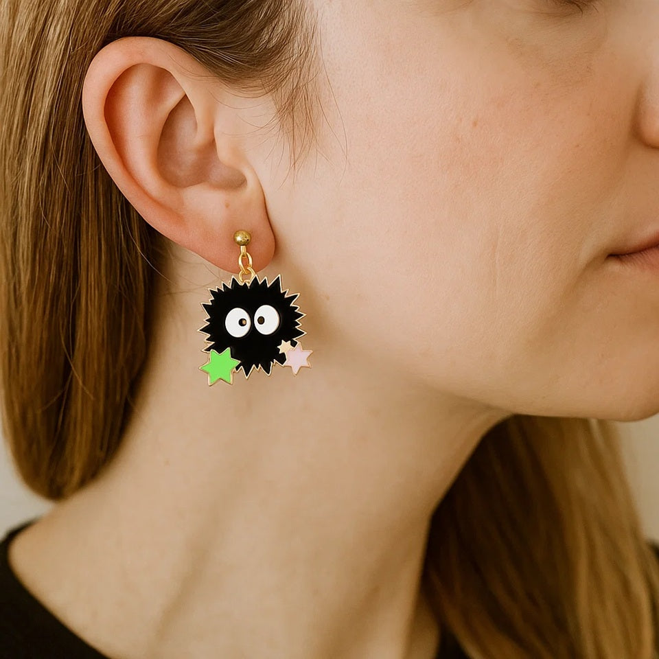 une paire de boucles d'oreilles en forme de noiraudes, ces petits êtres qui ressemblent à des boules de suie. Elles sont accompagnées de petites étoiles qui rappellent les sucreries dont elles raffolent.