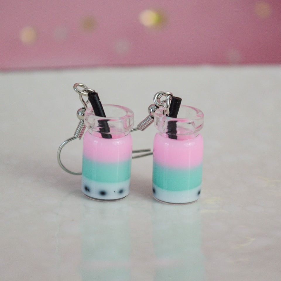 des boucles d'oreilles en forme de bubble tea de couleurs différentes. Certaines sont pailletées. Elles ont une paille pour plus de réalisme.