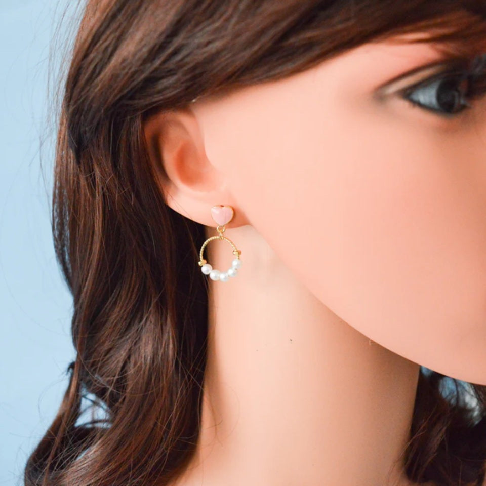 des boucles d'oreilles composées d'un coeur rose et d'une ronde de perles blanches pour un style romantique