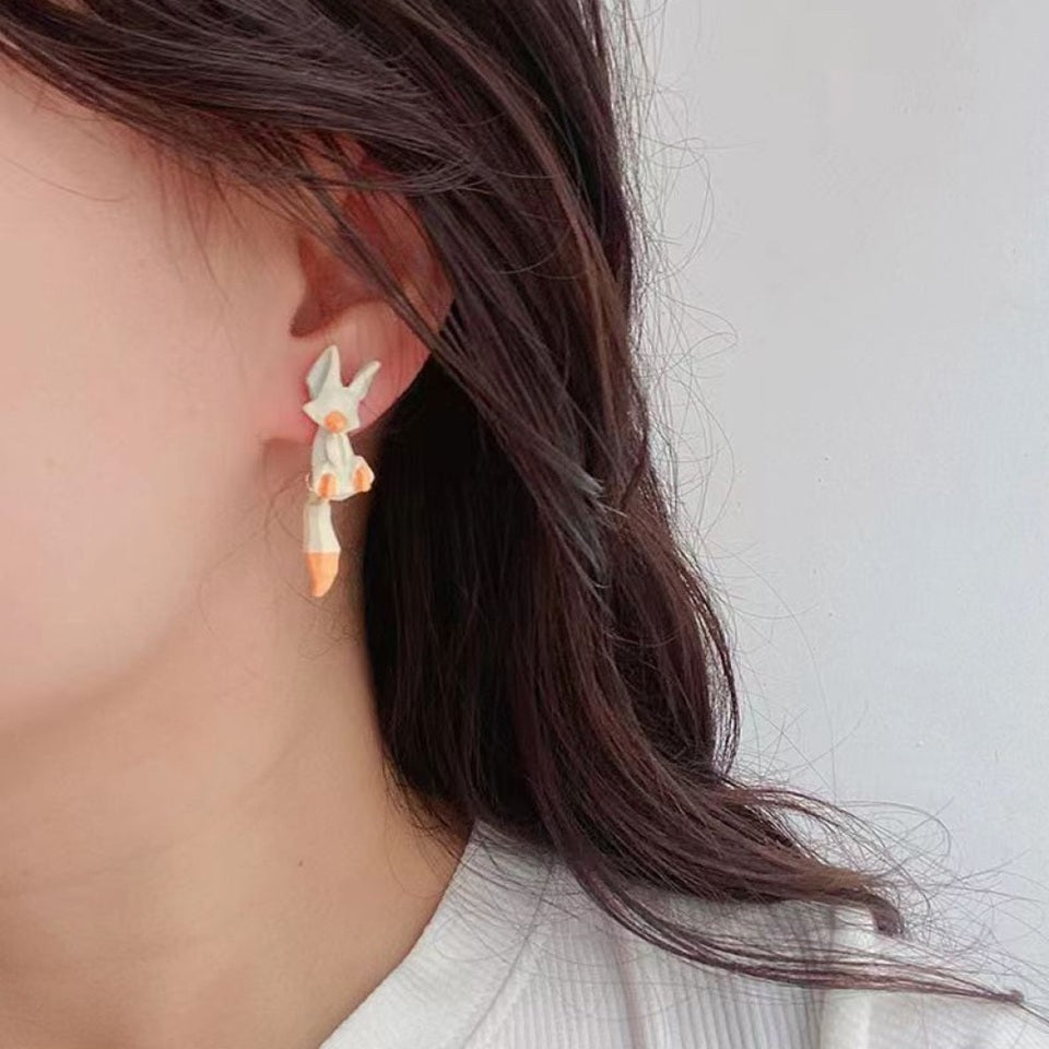 des boucles d'oreilles composées de deux renards : un blanc et un roux. Leur queue est pendante et le design est très mignon