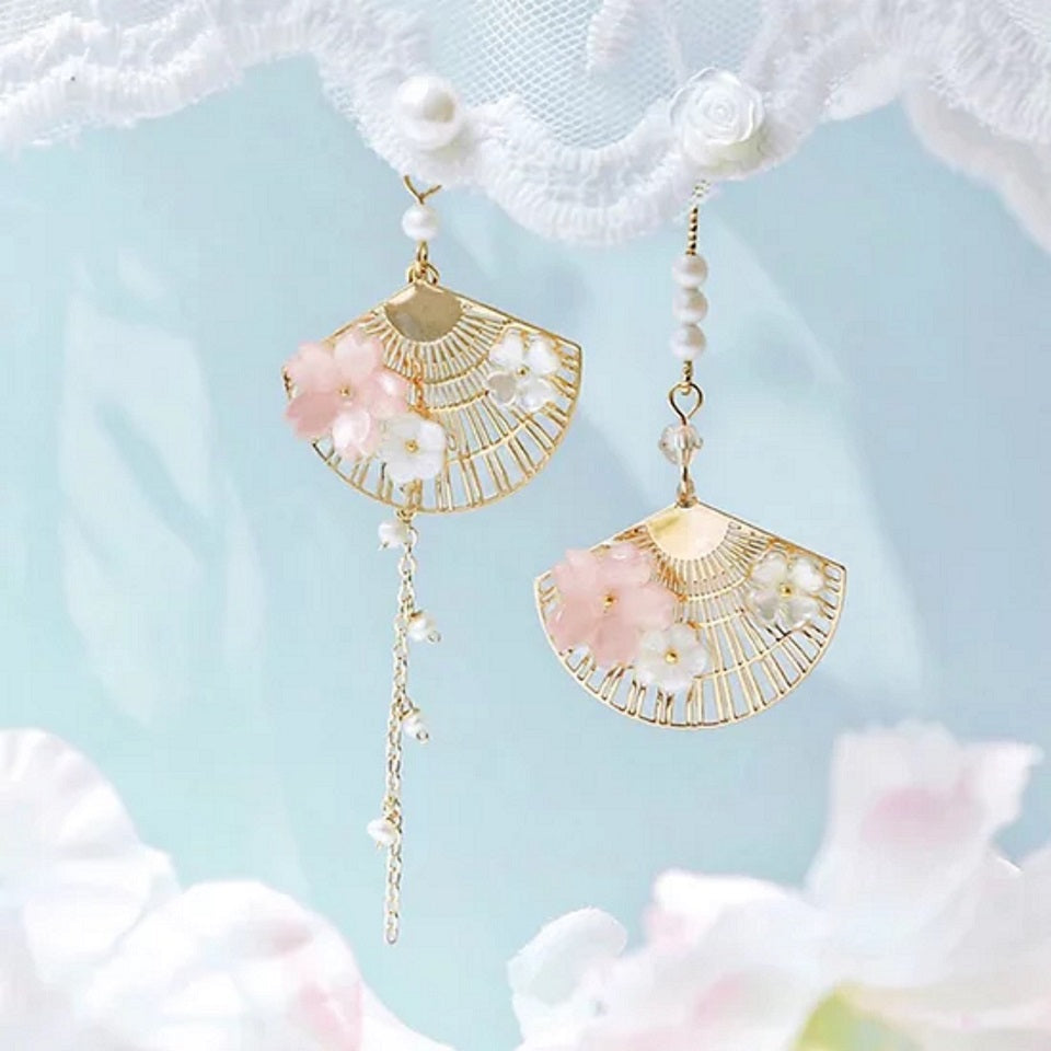 une paire de boucles d'oreilles asymétriques composées d'éventails dorés décorés avec de jolies fleurs de sakura, des perles blanches viennent apporter de l'élégance à l'ensemble.