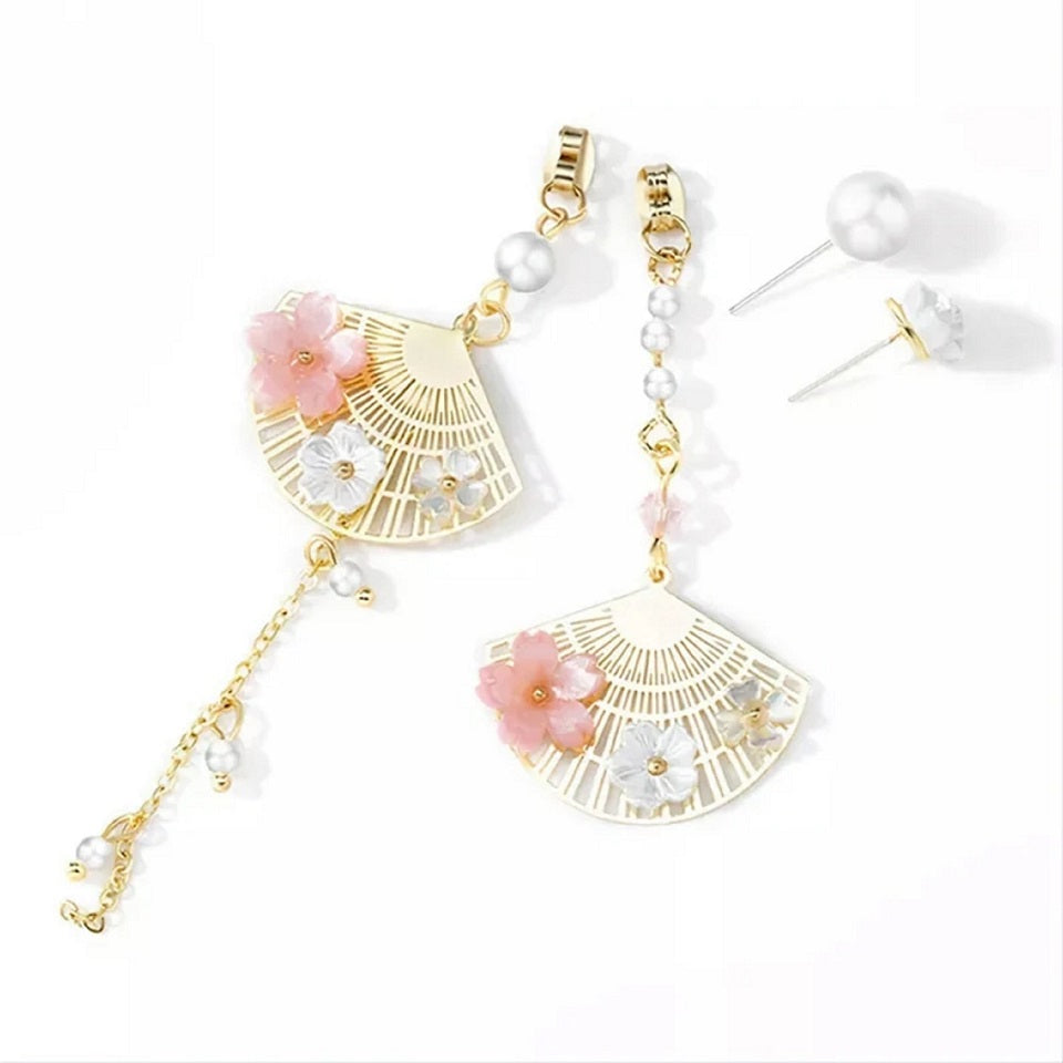 une paire de boucles d'oreilles asymétriques composées d'éventails dorés décorés avec de jolies fleurs de sakura, des perles blanches viennent apporter de l'élégance à l'ensemble.