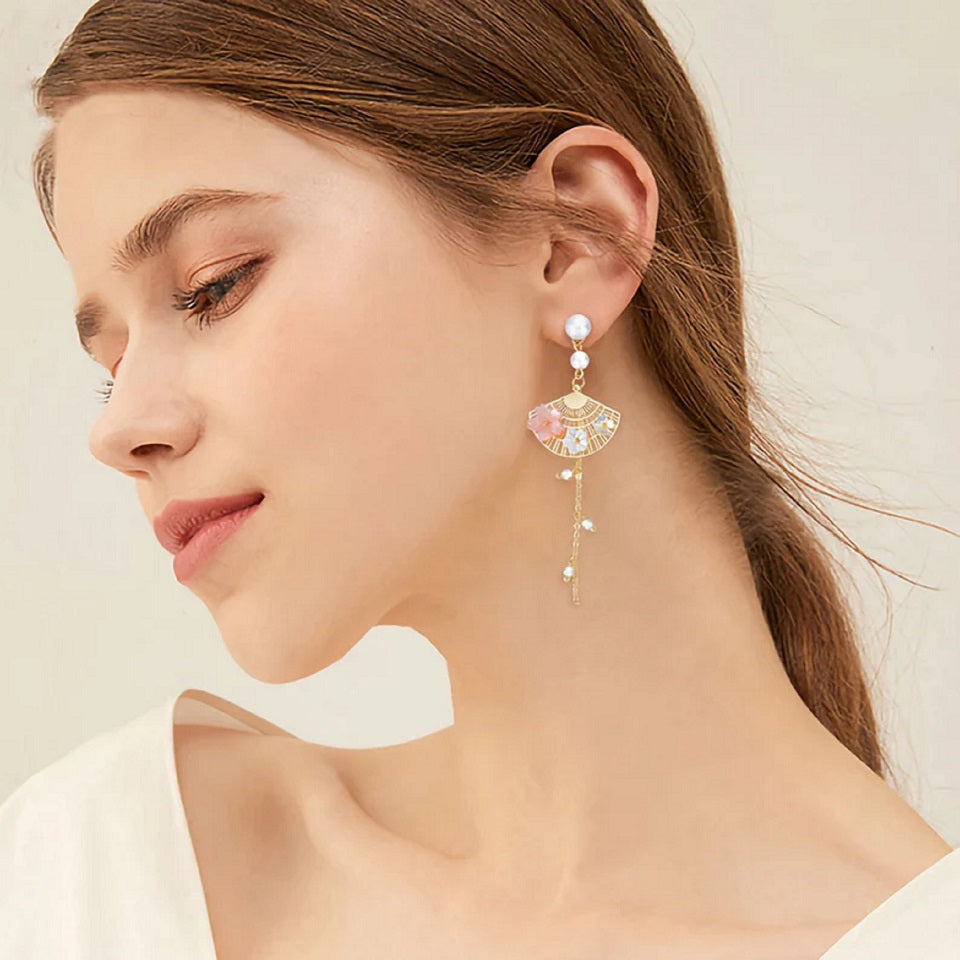 une paire de boucles d'oreilles asymétriques composées d'éventails dorés décorés avec de jolies fleurs de sakura, des perles blanches viennent apporter de l'élégance à l'ensemble.