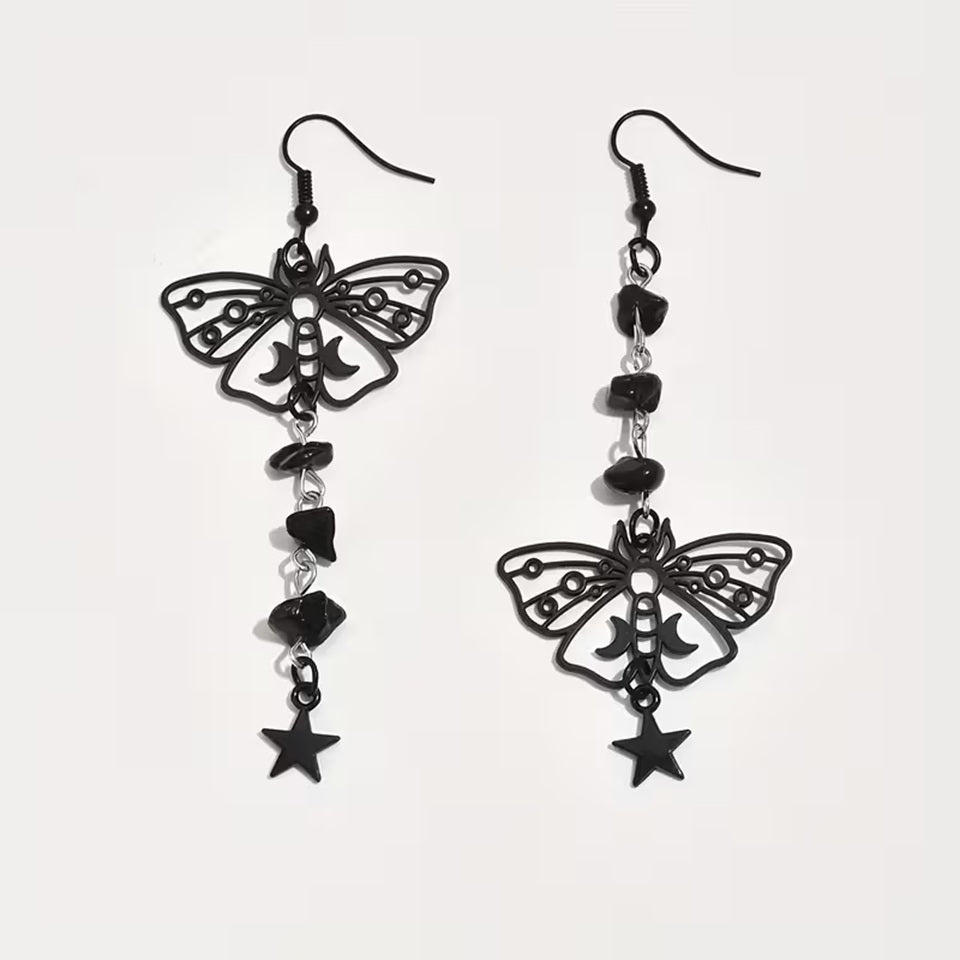 une paire de boucles d'oreilles en forme de papillons noirs orné de croissants de lune. De jolies pierres noires et étoiles pendent le long de la boucle pour un effet mystérieux et ésotérique.