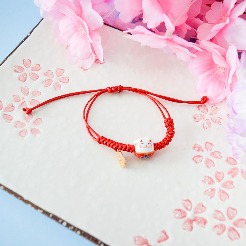 un bracelet en tissu en forme d'un maneki neko coloré avec sa plaquette dorée. Symbole de chance, de bonne fortune, il est inspiré du style japonais
