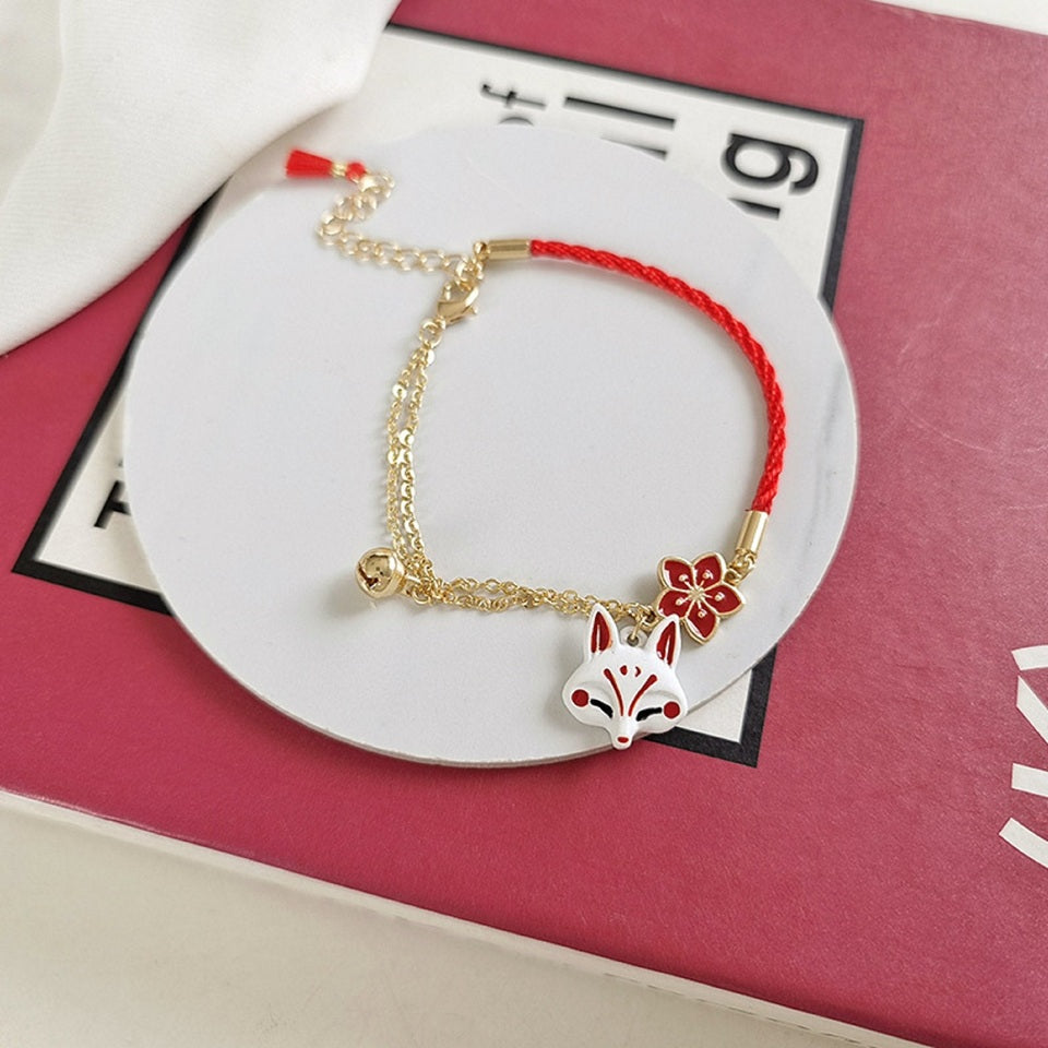 un bracelet kistune, une fleur de sakura rouge, une clochette adorable, le tout en coloris rouge et blanc. Harmonie parfaite. Inspiration du Japon