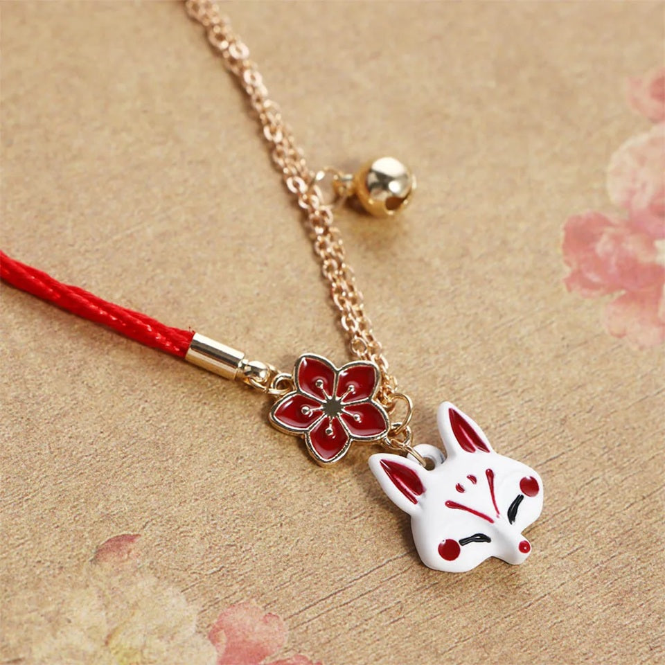 un bracelet kistune, une fleur de sakura rouge, une clochette adorable, le tout en coloris rouge et blanc. Harmonie parfaite. Inspiration du Japon