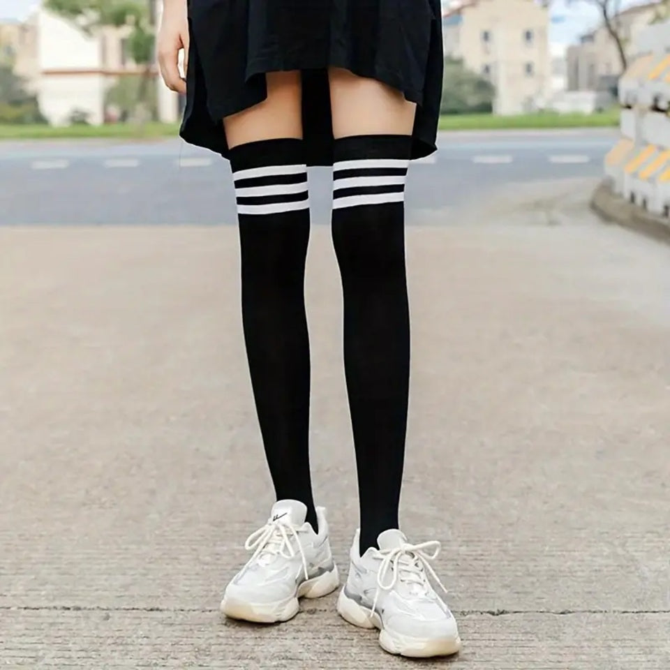 une paire de chaussettes noires hautes dont le haut présente des lignes blanches qui contrastent avec le noir de la chaussette
