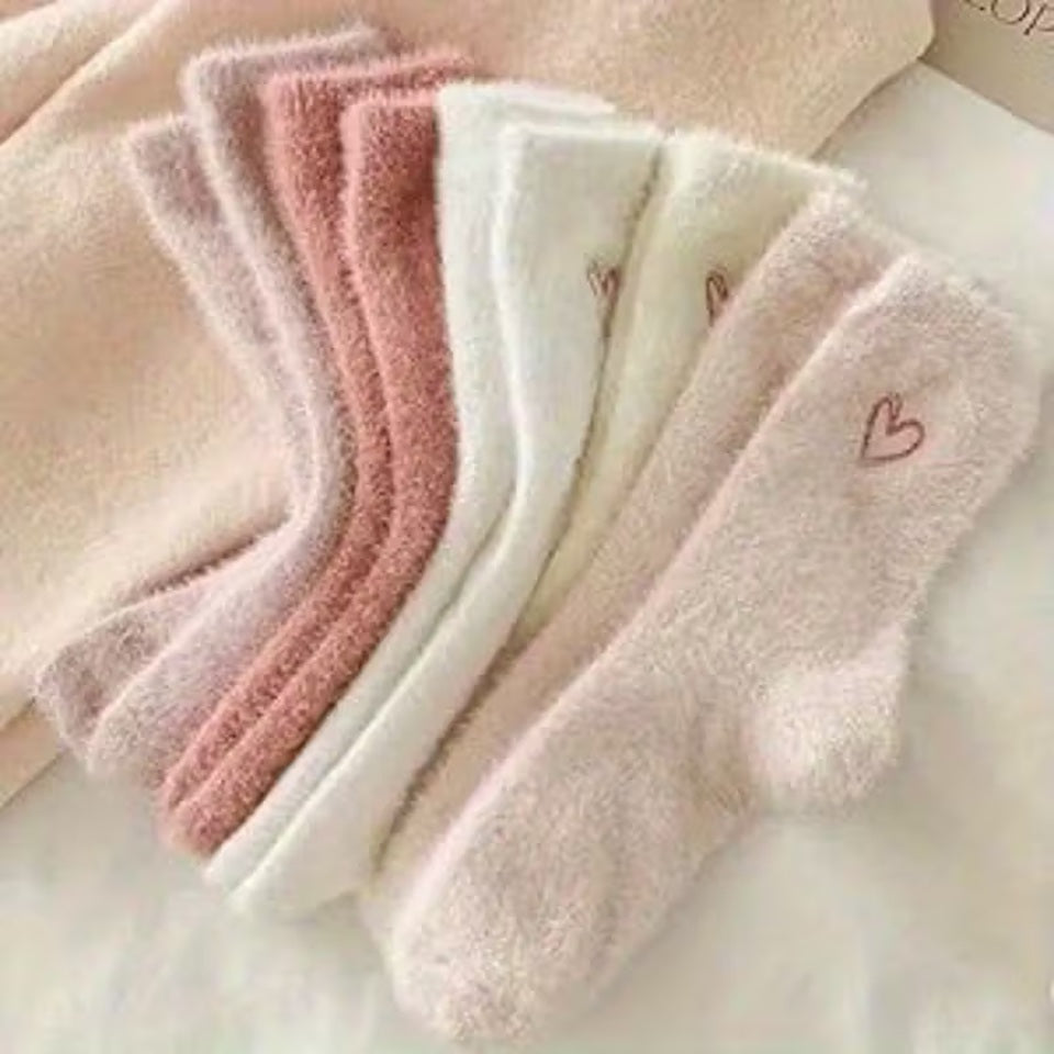 des paires de chaussettes toutes douces en matière pilou dans les tons roses et blancs. Sur le haut de la chaussette, un joli coeur rose est imprimé. Style féminin adorable, idéal pour les soirées cocooning !