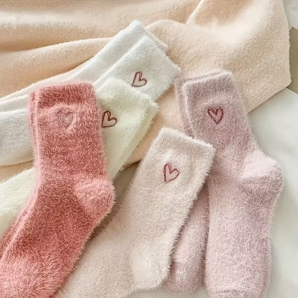 des paires de chaussettes toutes douces en matière pilou dans les tons roses et blancs. Sur le haut de la chaussette, un joli coeur rose est imprimé. Style féminin adorable, idéal pour les soirées cocooning !
