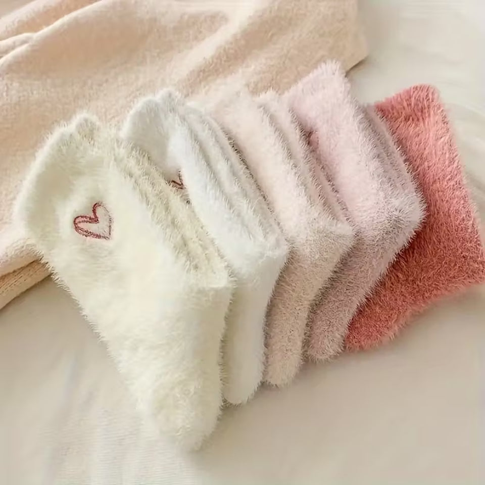 des paires de chaussettes toutes douces en matière pilou dans les tons roses et blancs. Sur le haut de la chaussette, un joli coeur rose est imprimé. Style féminin adorable, idéal pour les soirées cocooning !