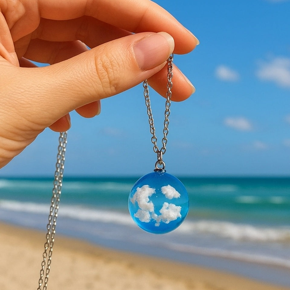 un joli collier argenté d'une sphÚre transparente et bleue renfermant des nuages comme si un bout d eciel y avait été capturé.