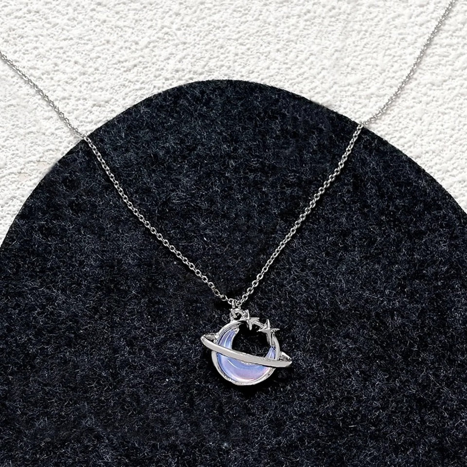 une collier argenté en forme d'une lune majestueuse aux reflets bleutés, un anneau scintillant l'entoure.