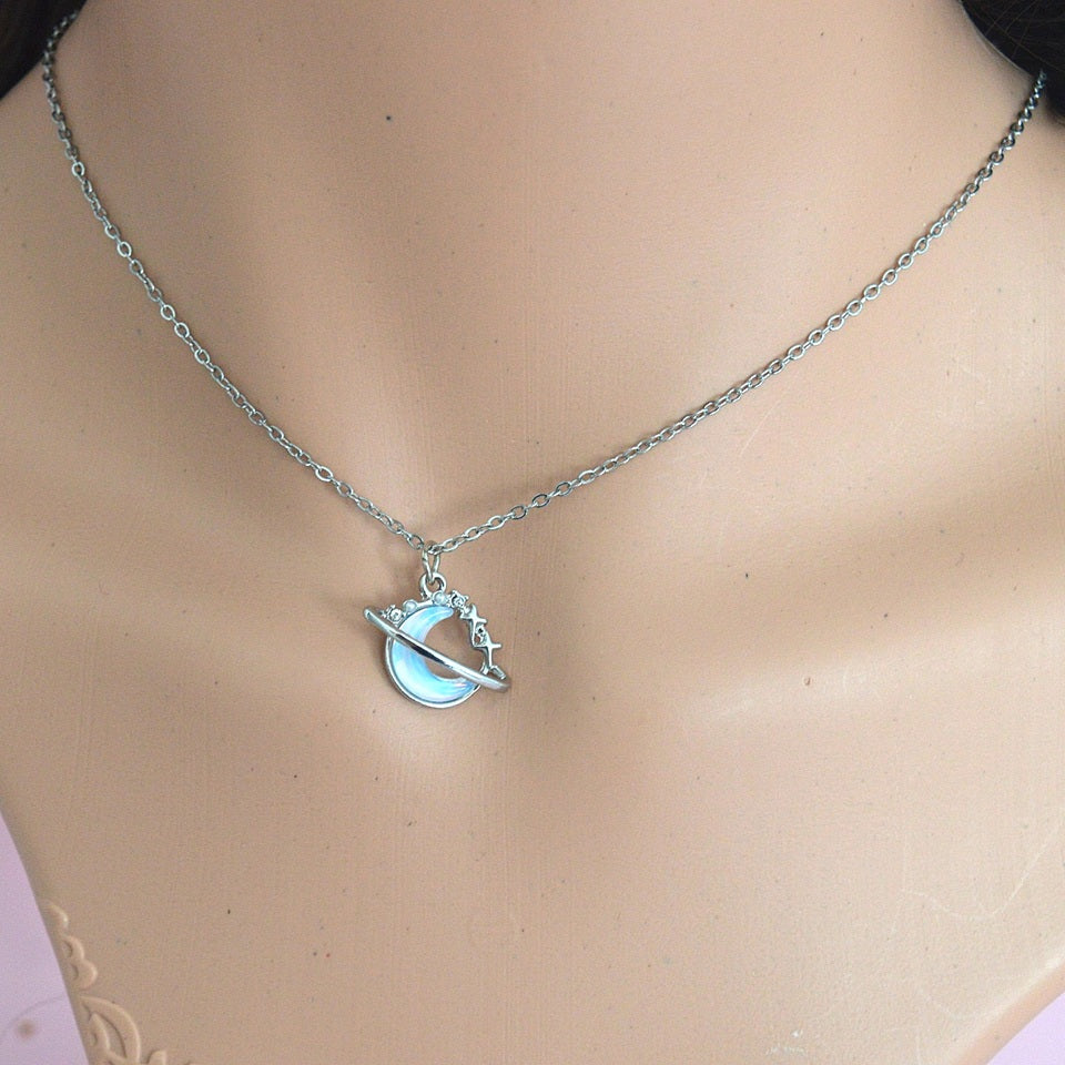 une collier argenté en forme d'une lune majestueuse aux reflets bleutés, un anneau scintillant l'entoure.