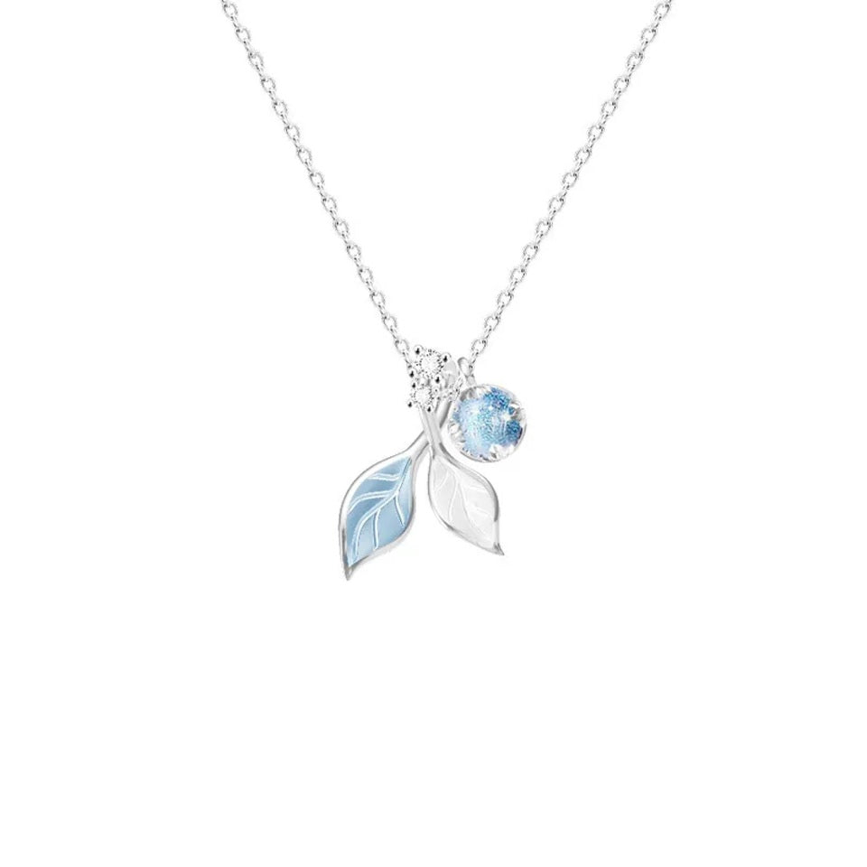 un collier argenté dont le pendentif représente de délicates feuilles bleues et d'une perle aux reflets bleutées. L'ensemble est poétique.