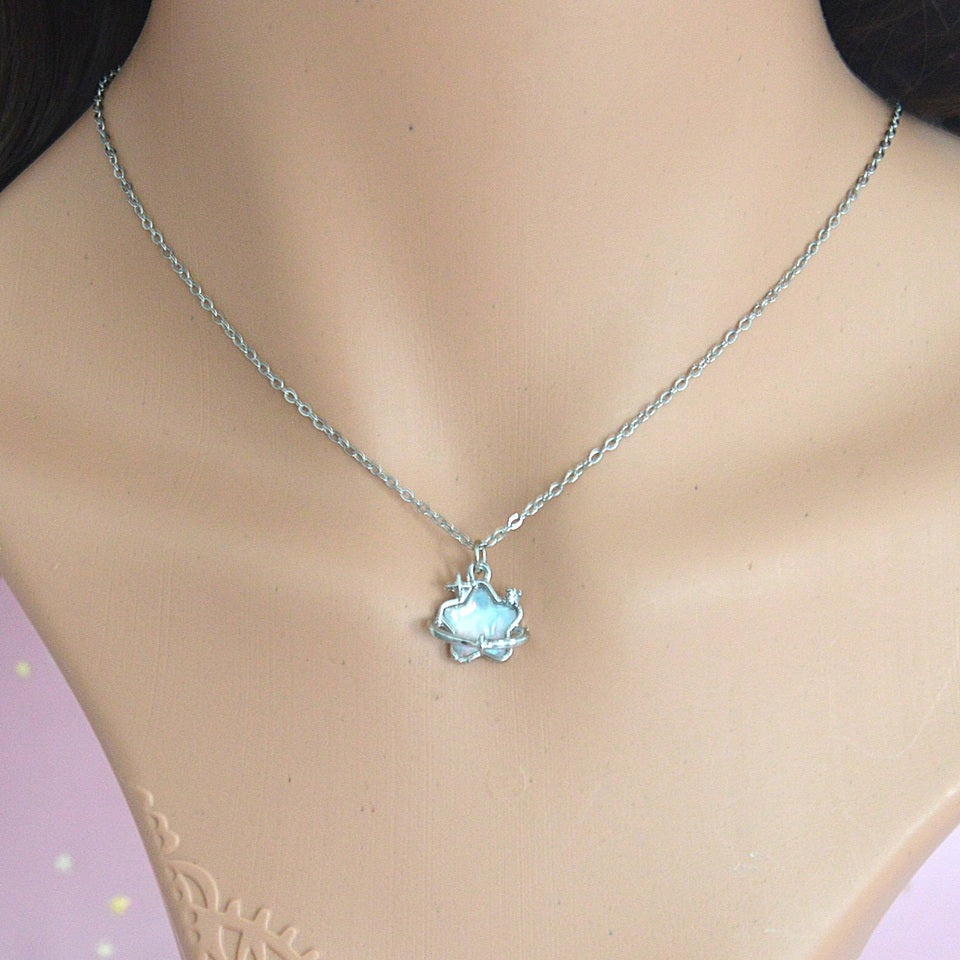 une collier unique et original en coloris argenté, d'une étoile aux reflets bleutés, entouré d'un anneau étoilé.
