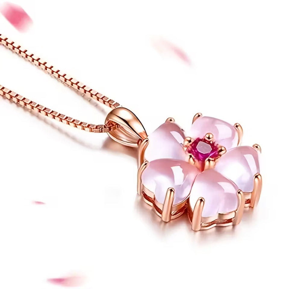 un superbe collier rose gold dont le pendentif est une jolie fleur de sakura aux pétales roses et dont le coeur est un strass rose brillant. Le bijou est élégant et romantique et rappelle la saison des sakura en fleurs au Japon.