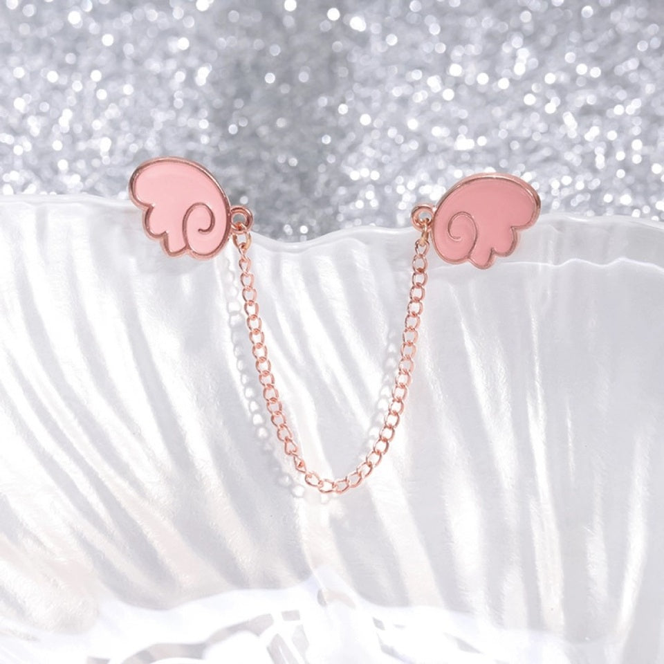 un double pin's en forme d'ailes rose façon chibi et kawaii reliés chacun à l'autre par une chainette rose gold.