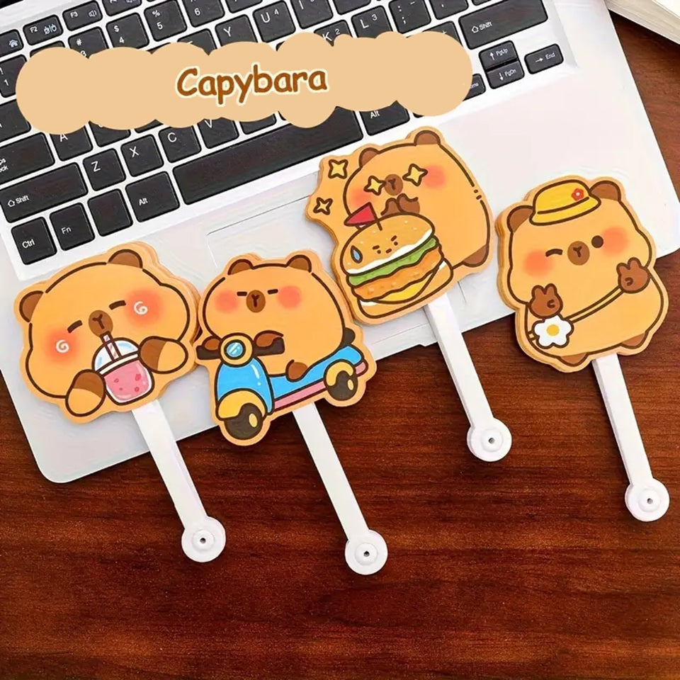 des éventails hyper rigolos et fun dont les lames sont des capybaras dans différentes situations amusantes : devant un hamburger, en scooter, en train de boire ou tout simplement content.