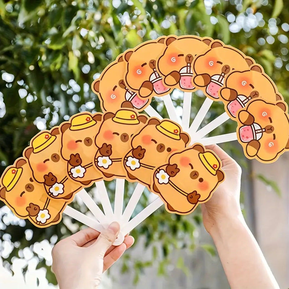 des éventails hyper rigolos et fun dont les lames sont des capybaras dans différentes situations amusantes : devant un hamburger, en scooter, en train de boire ou tout simplement content.