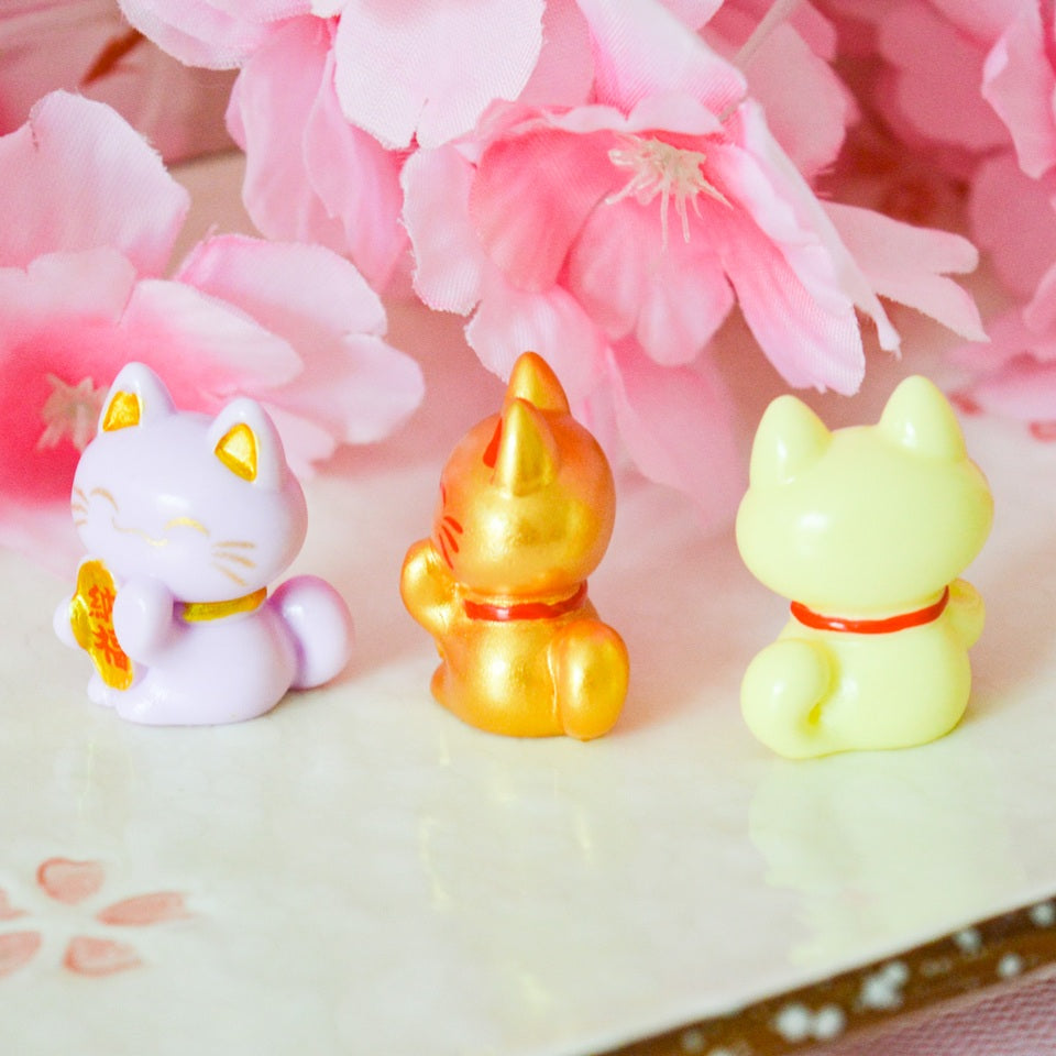 des petites figurines en forme de maneki neko de plusieurs couleurs différentes : jaune, blanc, vert, mauve, rouge, noir, rose, dorée et vert. Elles sont considérées comme porte-bonheur au Japon. Elles peuvent servir comme élément de décoration.