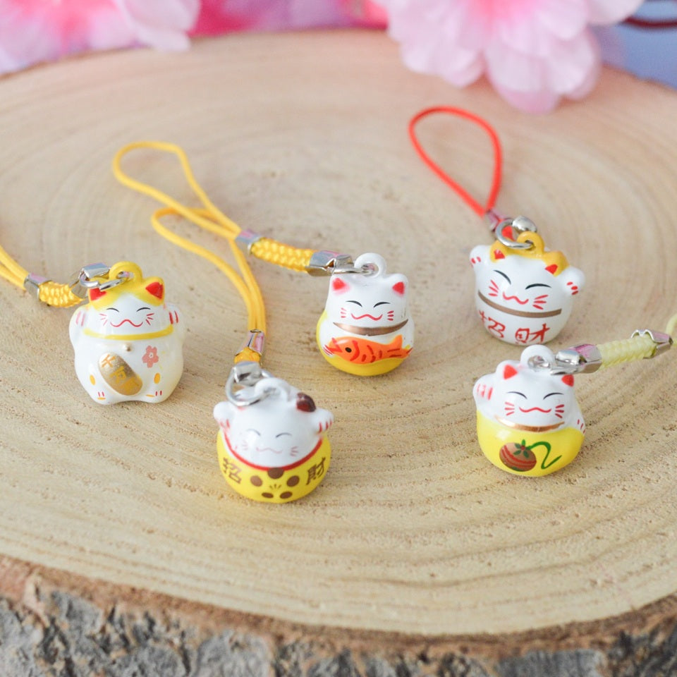des porte-clés en forme de maneki neko sous forme de grelot. Il y a plusieurs couleurs et designs différents.