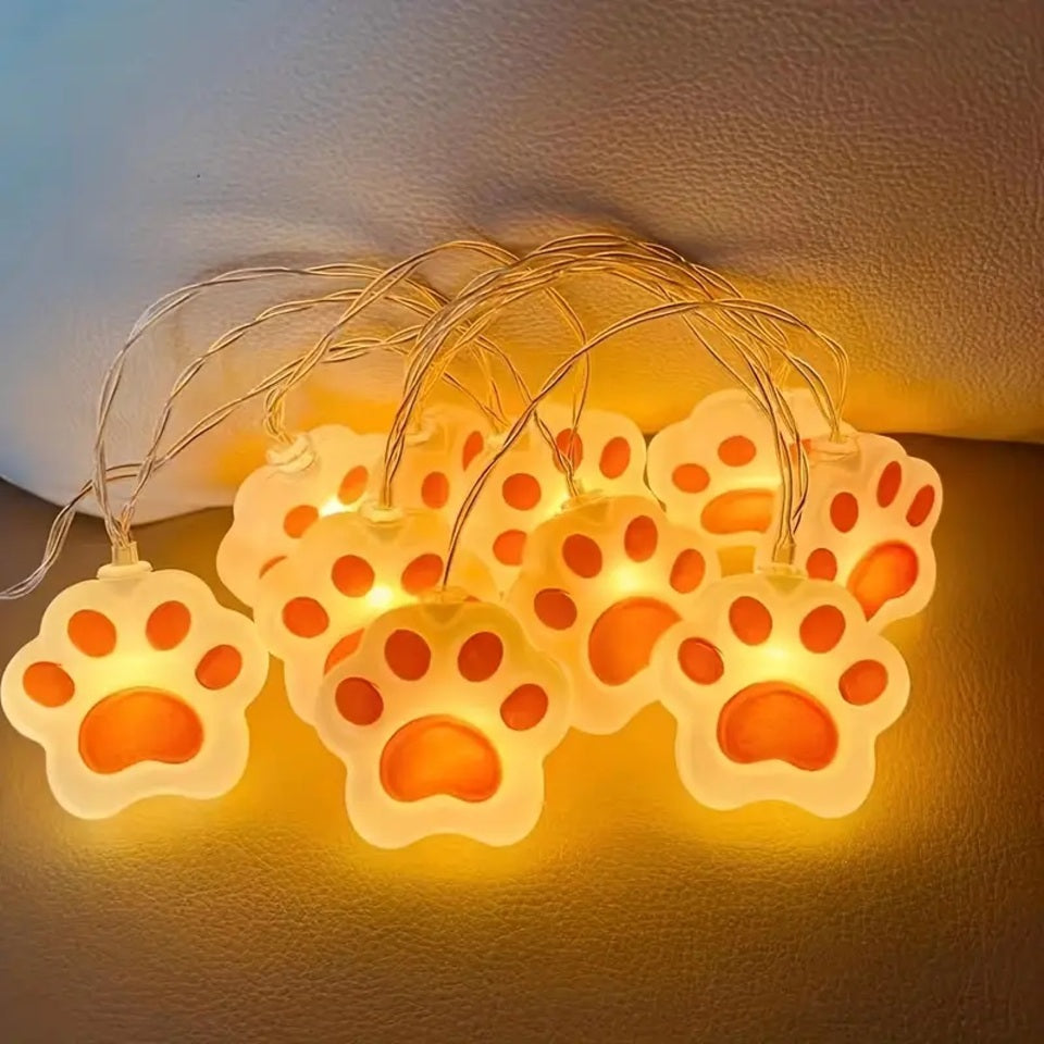 une guirlande LED en forme de pattes de chat roses toutes mignonnes. Elle diffuse une lumière jaune douce et chaleureuse. Idéal pour un coin cocooning.