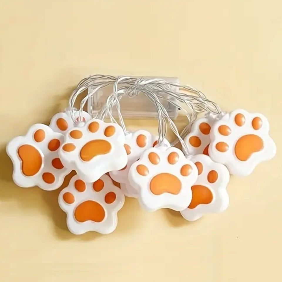 une guirlande LED en forme de pattes de chat roses toutes mignonnes. Elle diffuse une lumière jaune douce et chaleureuse. Idéal pour un coin cocooning.