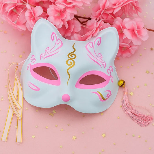 un masque kitsune rose avec des détails dorés, pompons et clochettes. Idéal pour un cosplay, une soirée déguisée ou en décoration.
